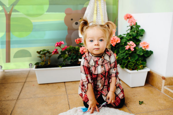 Little girl playing on the balcony in the background a pot of flowers